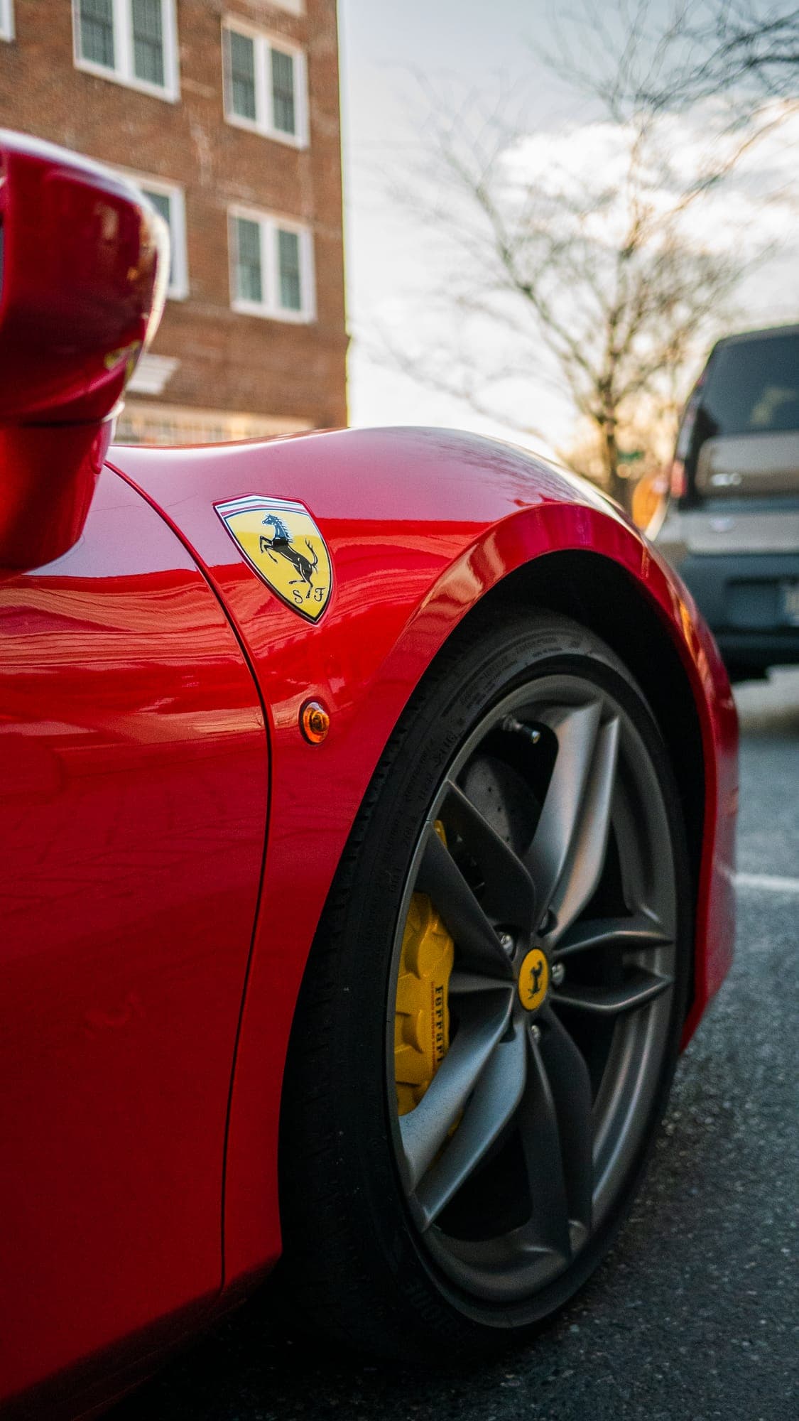 Ferrari shield badge and yellow brake caliper behind the front wheel of a red 488.