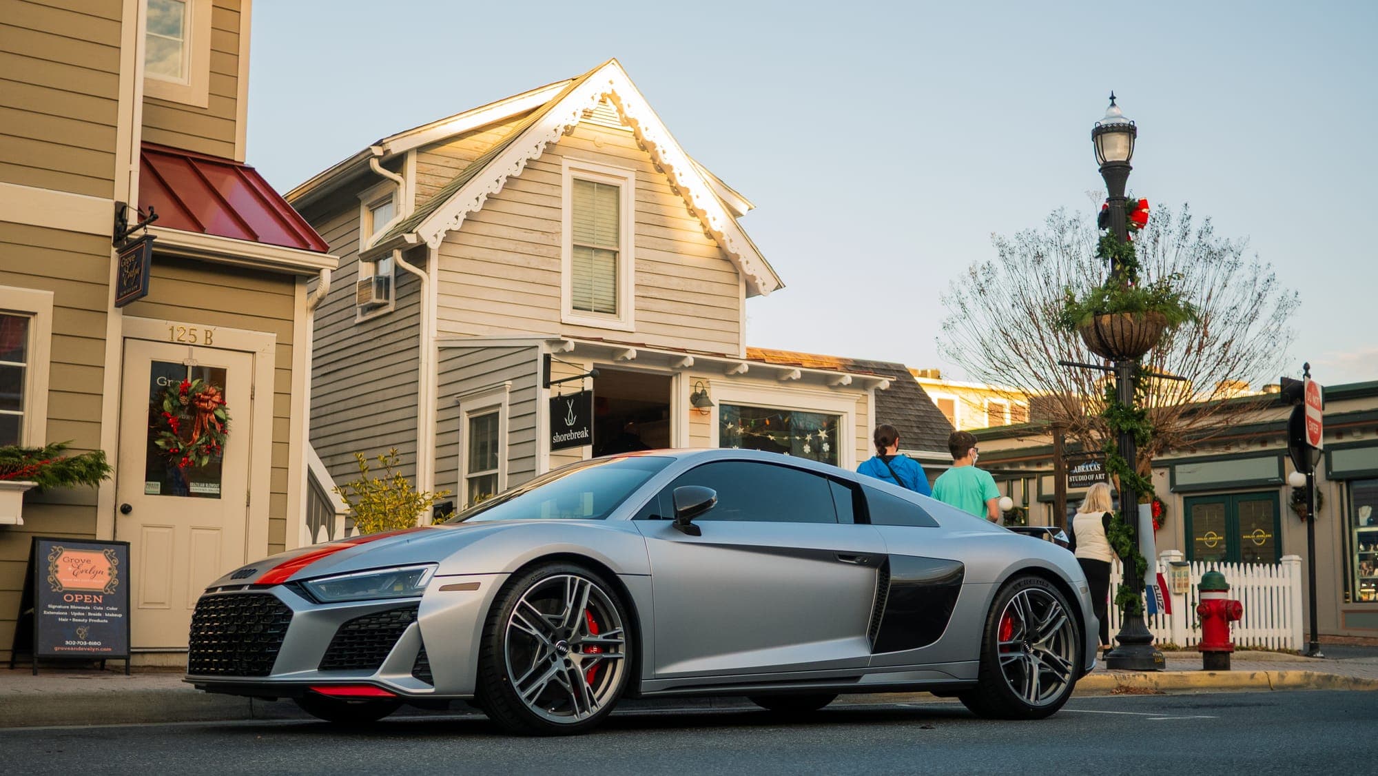 Silver Audi R8 V10 in side profile on a small-town street lined with Victorian storefronts.