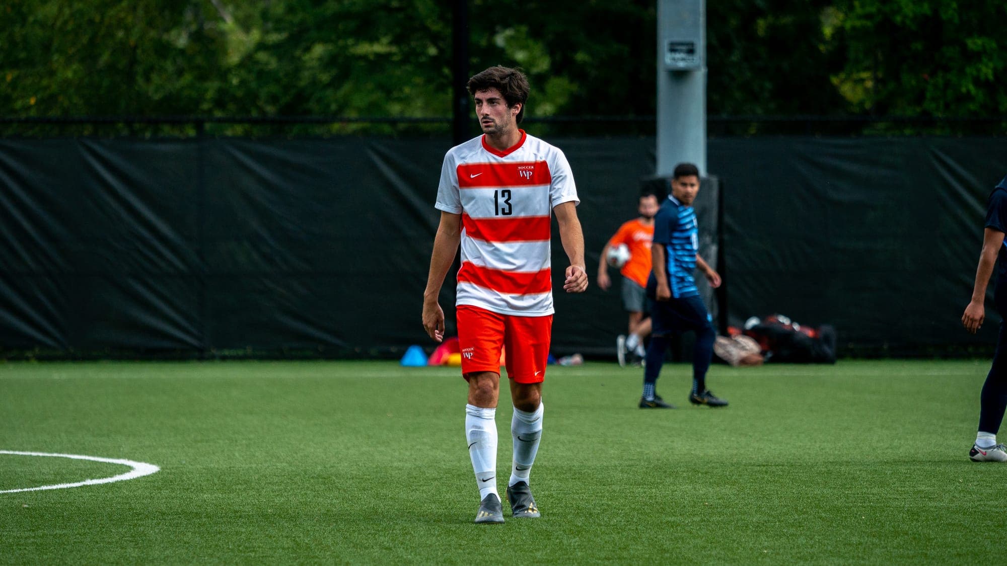 Soccer player number 13 walking alone across the turf between phases of play
