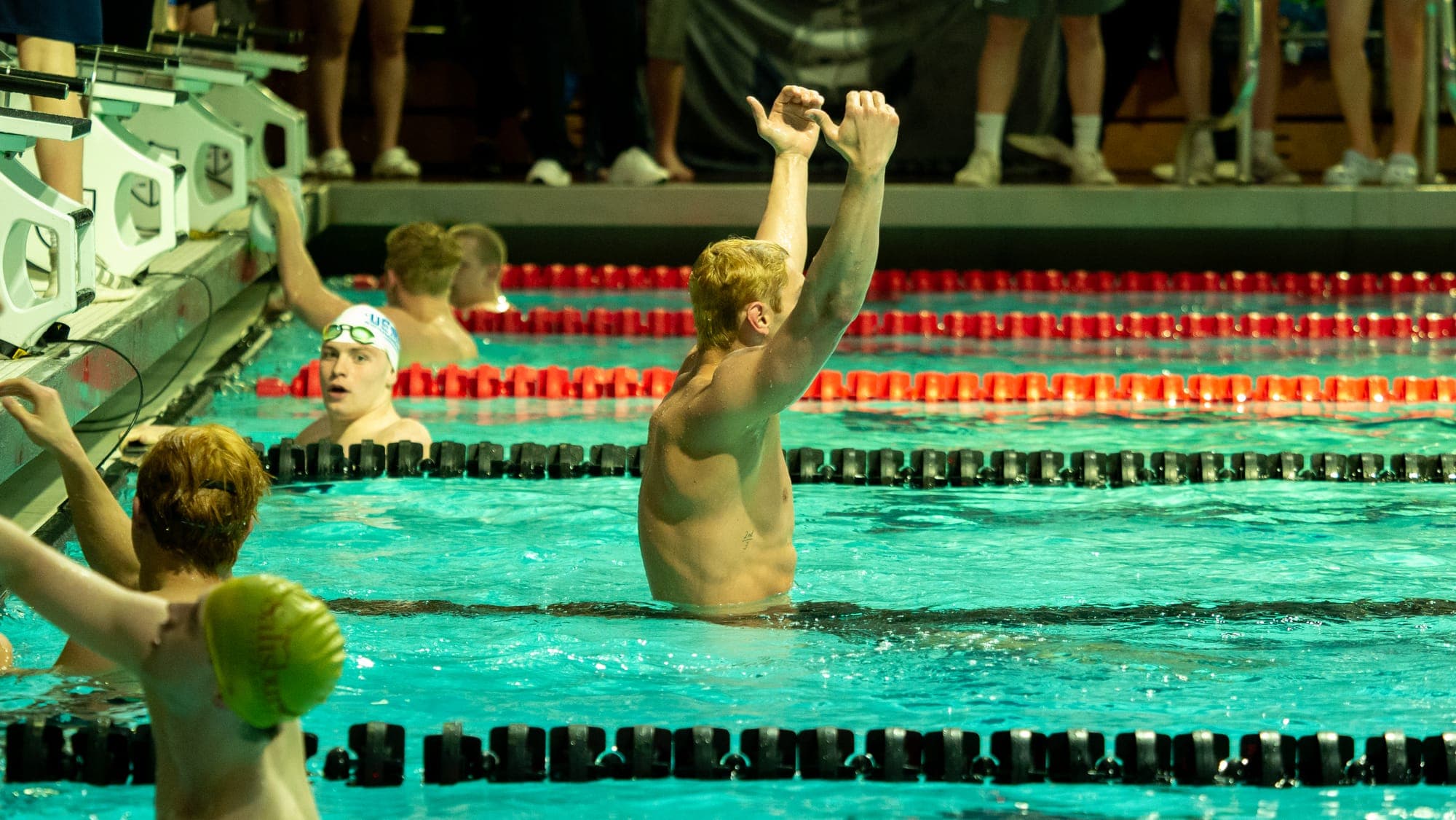 Swimmer thrusting both fists overhead in the water after winning a race