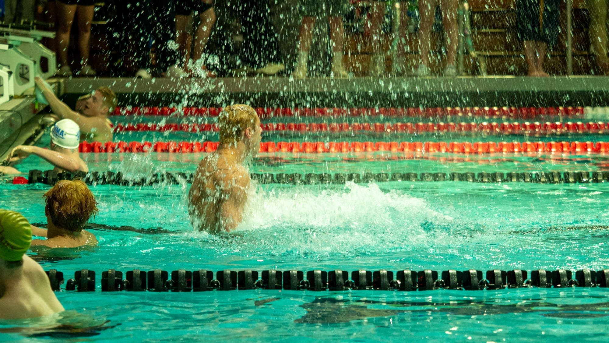 Swimmer whipping up a curtain of spray in celebration at the end of a race