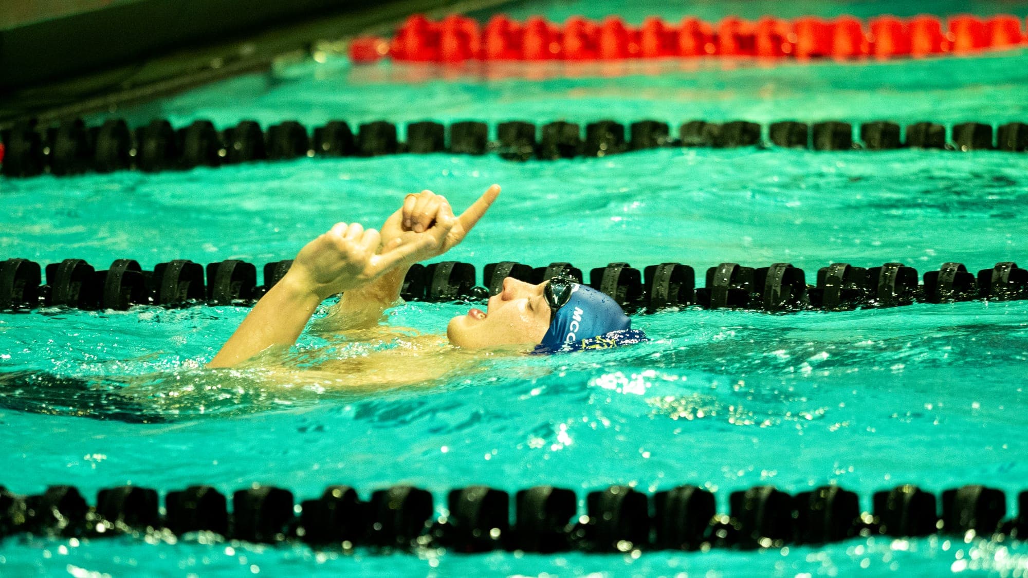 Backstroker on the surface after a finish, both index fingers pointed to the ceiling