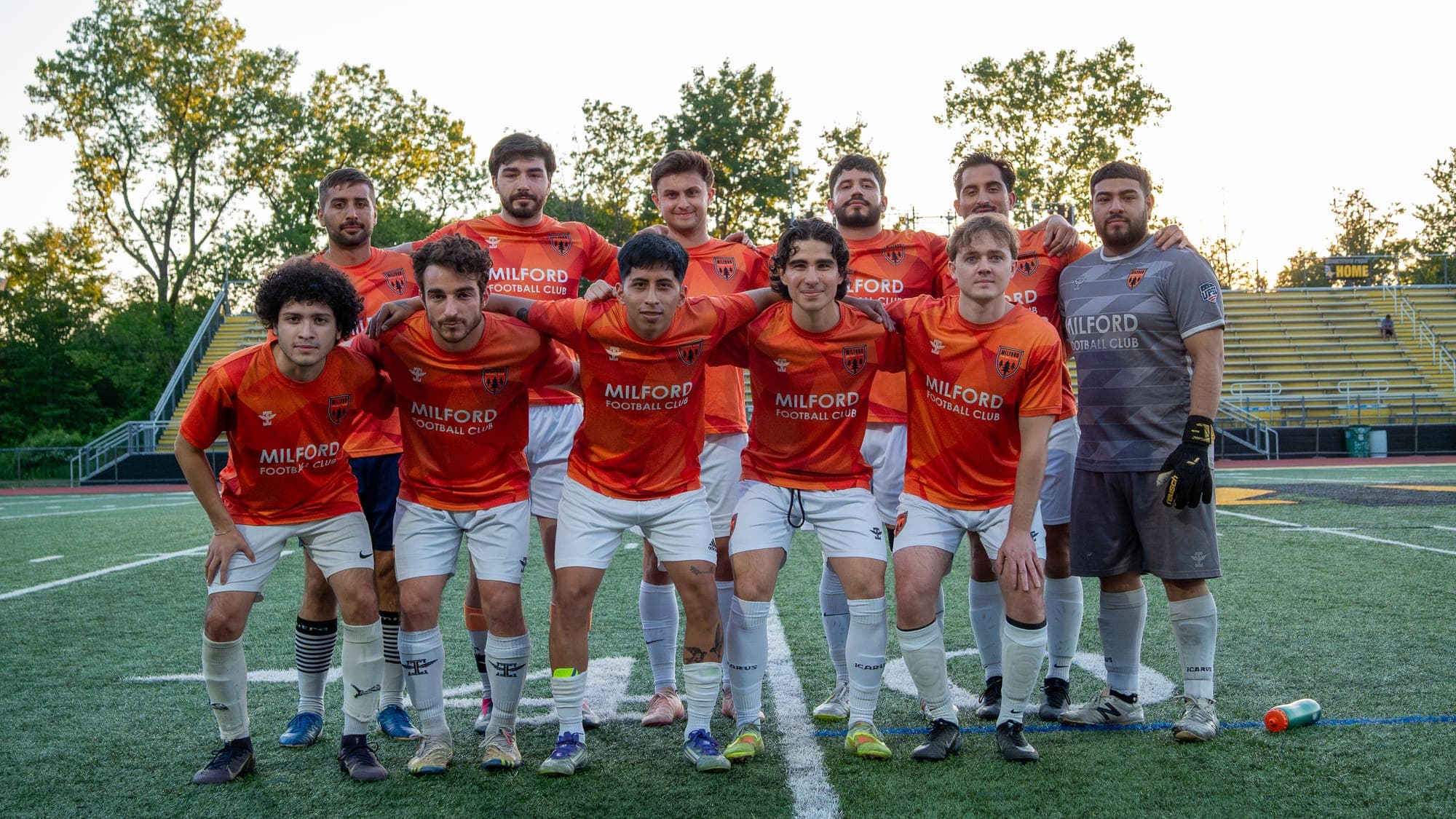 Soccer team in orange jerseys posed together on the turf for a pre-match group photo