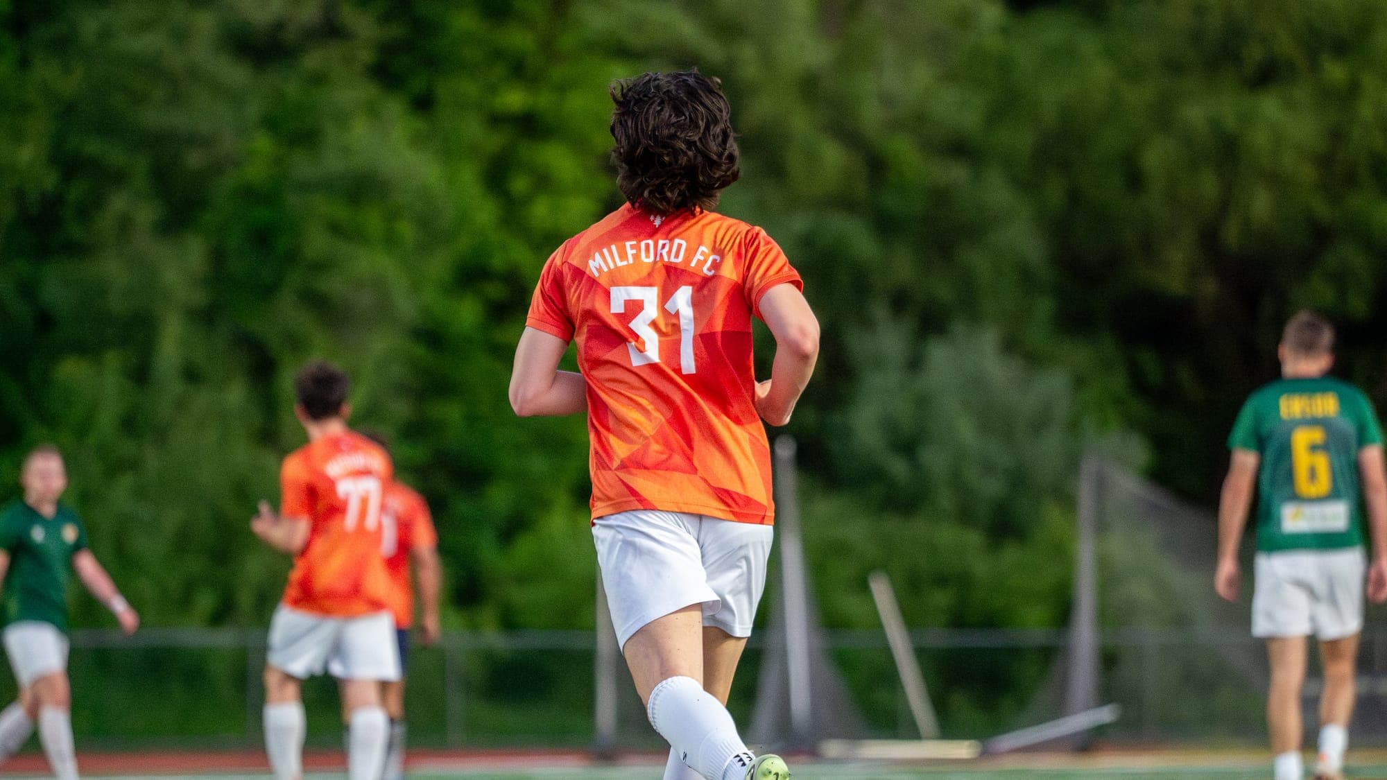 Milford FC number 31 seen from behind, jogging back into position between plays